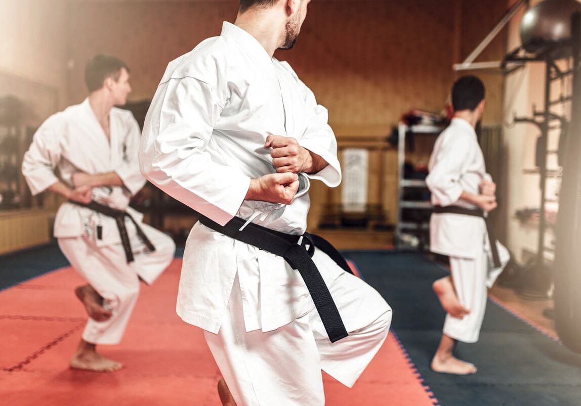 Martial artists practicing self-defense techniques in a well-equipped training facility.